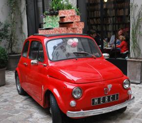 Een rode miniauto bij de ingang van de Merci winkel in Le Marais, Parijs